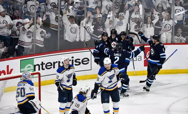 Winnipeg Jets' Mark Scheifele (55) celebrates his goal on St. Louis Blues goaltender Jordan Binnington (50) with teammates during the first period of an NHL hockey playoff game in Winnipeg, Manitoba, Monday April 21, 2025. (Fred Greenslade/The Canadian Press via AP)
