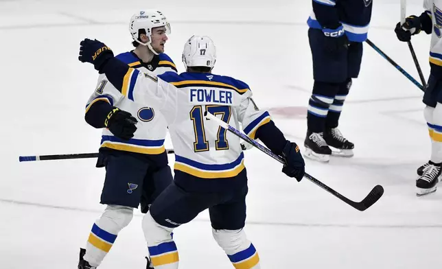St. Louis Blues' Jimmy Snuggerud, left, celebrates after his goal against the Winnipeg Jets with Cam Fowler (17) during the first period of Game 2 of a first-round NHL hockey playoff series in Winnipeg, Manitoba, Monday April 21, 2025. (Fred Greenslade/The Canadian Press via AP)