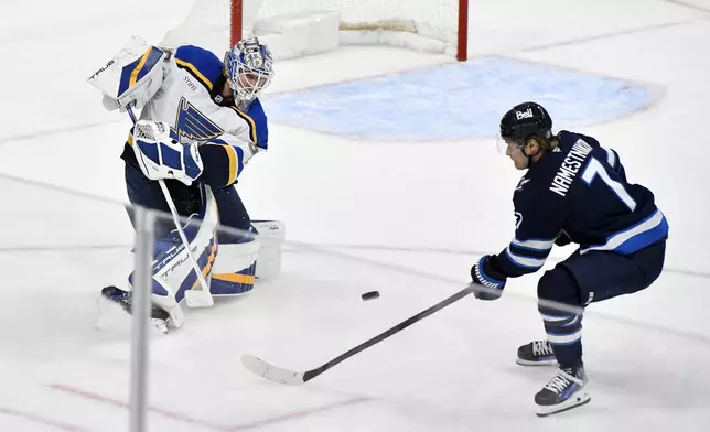 St. Louis Blues goaltender Jordan Binnington, left, clears the puck away from Winnipeg Jets' Vladislav Namestnikov (7) during the third period of Game 2 of a first-round NHL hockey playoff series in Winnipeg, Manitoba, Monday April 21, 2025. (Fred Greenslade/The Canadian Press via AP)
