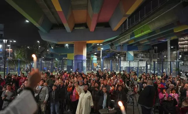 Faithful hold candles under a highway bridge during Mass to honor the late Pope Francis in the Carlos Mugica neighborhood of Buenos Aires, Argentina, Monday, April 21, 2025. (AP Photo/Rodrigo Abd)