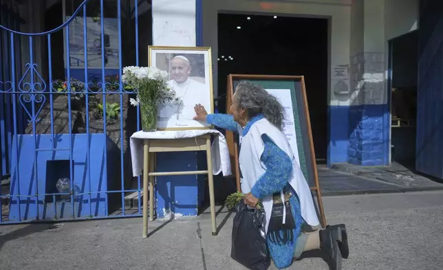 Gregoria Caceres kneels in front of a portrait of the late Pope Francis at the Caacupe Parish, which he often visited and preached at, in Buenos Aires, Argentina, Monday, April 21, 2025. (AP Photo/Natacha Pisarenko)