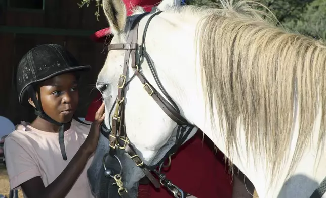 Merci who participates in the "Enabling Through the Horse," therapy program outside Windhoek, Namibia, pets a horse on Feb. 18, 2025. (AP Photo/Dirk Heinrich)