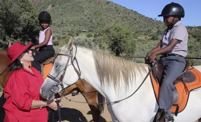 Susan de Meyer assists children participating in the "Enabling Through the Horse," therapy program outside Windhoek, Namibia, on Feb. 18, 2025. (AP Photo/Dirk Heinrich)