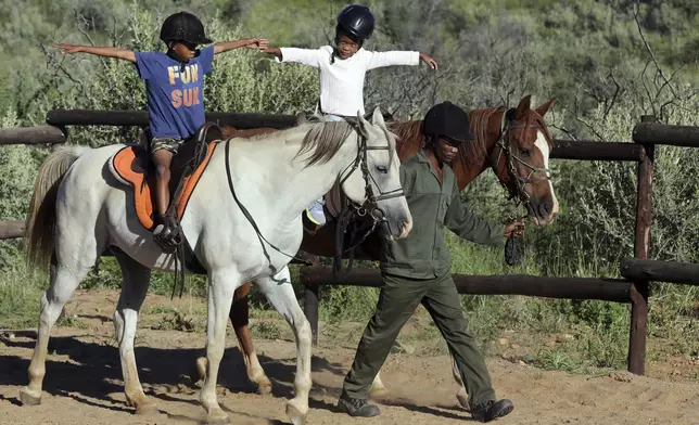 Immanuel Hoxobeb assists children participating in the "Enabling Through the Horse," therapy program outside Windhoek, Namibia, on Feb. 18, 2025. (AP Photo/Dirk Heinrich)