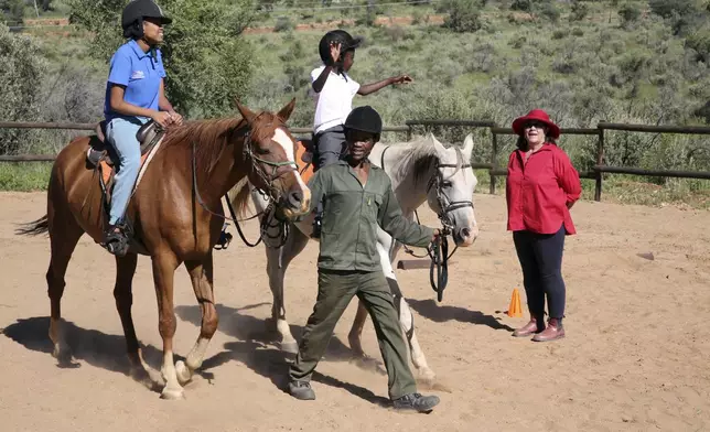 Susan de Meyer, right, and Immanuel Hoxobeb assist children participating in the "Enabling Through the Horse," therapy program outside Windhoek, Namibia, on Feb. 18, 2025. (AP Photo/Dirk Heinrich)