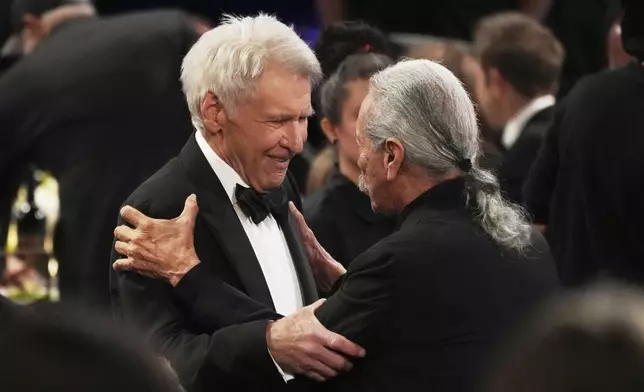 Harrison Ford, left, and Edward James Olmos greet each other during the 50th AFI Life Achievement Award tribute to Francis Ford Coppola on Saturday, April 26, 2025, at the Dolby Theatre in Los Angeles. (AP Photo/Chris Pizzello)