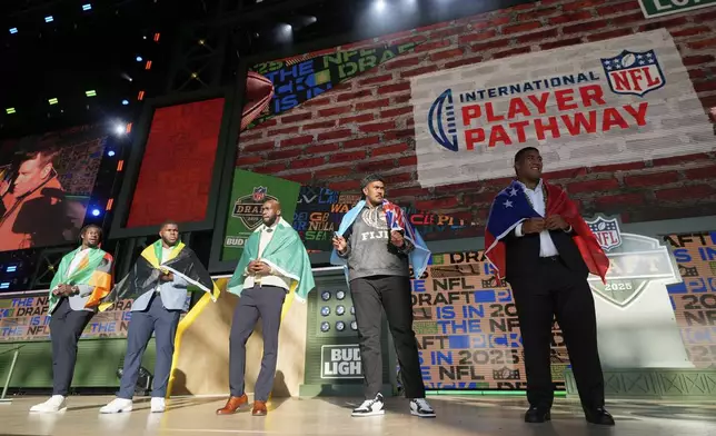Players from the International Player Pathway stand on stage during the third day of the NFL football draft, Saturday, April 26, 2025, in Green Bay, Wis. (AP Photo/Jeff Roberson)