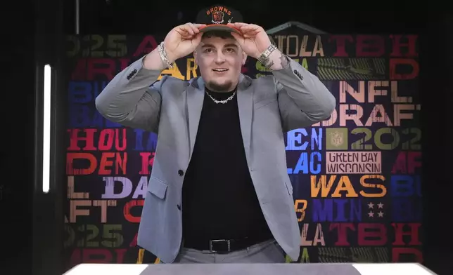 Michigan defensive lineman Mason Graham puts on a hat after being chosen by the Cleveland Browns with the fifth overall pick during the first round of the NFL football draft, Thursday, April 24, 2025, in Green Bay, Wis. (AP Photo/Jeff Roberson)