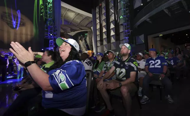 Seattle Seahawks fan Jos Cameron, a 22-year season ticket holder, applauds at the start of an NFL football draft party at the Museum of Pop Culture, Thursday, April 24, 2025, in Seattle. (AP Photo/John Froschauer)