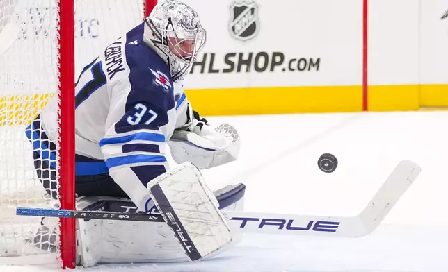 Winnipeg Jets goaltender Connor Hellebuyck blocks a shot by the Dallas Stars during the first period of an NHL hockey game Thursday, April 10, 2025, in Dallas. (AP Photo/Julio Cortez)