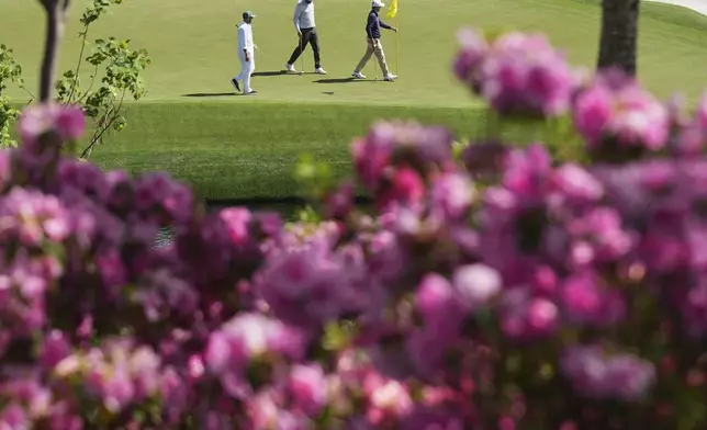 Scottie Scheffler, center, and Russell Henley, right, walk off the green on the 16th hole during a practice around at the Masters golf tournament, Wednesday, April 9, 2025, in Augusta, Ga. (AP Photo/Matt Slocum)