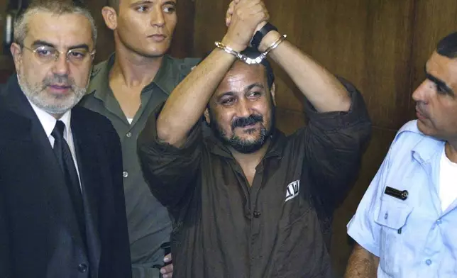 FILE - Marwan Barghouti, center, raises his handcuffed hands in the air on the opening day of his trial in Tel Aviv, Israel, Aug. 14, 2002. (AP Photo/Brennan Linsley, File)
