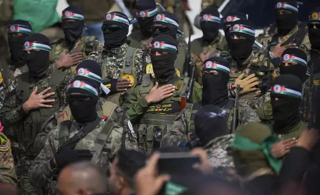 FILE - Hamas fighters stand in formation ahead of a ceremony to hand over Israeli hostages to the Red Cross in Nuseirat, Gaza Strip, Feb. 22, 2025. (AP Photo/Abdel Kareem Hana, File)