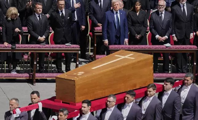 The coffin of Pope Francis is carried in front of dignitaries, including President Donald Trump, center, and French President Emmanuel Macron, during his funeral in St. Peter's Square at the Vatican, Saturday, April 26, 2025. (AP Photo/Gregorio Borgia)