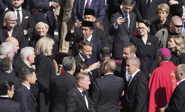 French President Emmanuel Macron, center, speaks with guests as he arrives for the funeral of Pope Francis in St. Peter's Square at the Vatican, Saturday, April 26, 2025. (AP Photo/Markus Schreiber)