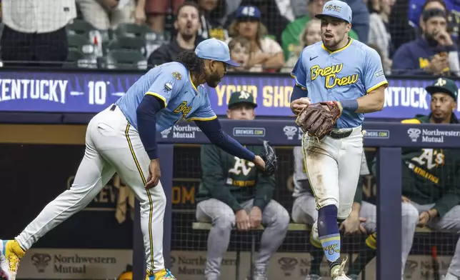Milwaukee Brewers' Caleb Durbin, right, reacts with Brewers pitcher Freddy Peralta after catching a foul ball hit by Athletics' Lawrence Butler during the fifth inning of a baseball game, Friday, April 18, 2025, in Milwaukee. (AP Photo/Jeffrey Phelps)