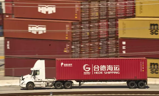 A truck carrying a Hede (Hong Kong) International Shipping Co., Ltd., container moves along the Port of Los Angeles Wednesday, April 9, 2025 in Los Angeles. (AP Photo/Damian Dovarganes)