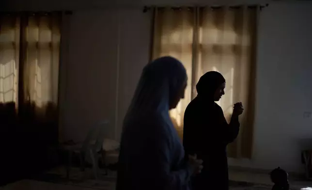 A woman and her mother, both of whom did not want to be named for fear of reprisal, stand in a wedding hall at a charity center that is being used as a temporary shelter for displaced people in the West Bank town of Anabta, Thursday, April 3, 2025. (AP Photo/Leo Correa)
