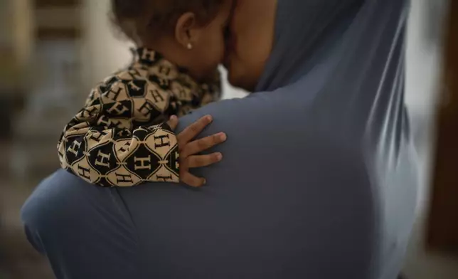 A 52-year-old family matriarch, who did not want to be named for fear of reprisal, kisses a granddaughter in a wedding hall at a charity center that has been used as a temporary shelter for displaced people in the West Bank town of Anabta, Thursday, April 3, 2025. (AP Photo/Leo Correa)