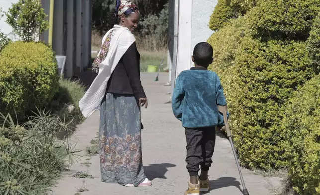 A young boy who lost his leg during the recent war walks with his mother during a visit at Ortho-Physiotherapy Centre in Mekele, Tigray region of northern Ethiopia Friday, Feb. 14, 2025. (AP Photo/Amanuel Birhane)