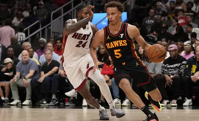 Atlanta Hawks guard Dyson Daniels (5) dribbles against Miami Heat forward Haywood Highsmith (24) in the first half of an NBA play-in tournament basketball game, Friday, April 18, 2025, in Atlanta. (AP Photo/Brynn Anderson)