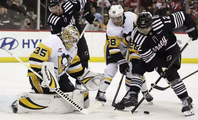 Pittsburgh Penguins goaltender Tristan Jarry defends his net against New Jersey Devils center Cody Glass (12) in the second period of an NHL hockey game Friday, April 11, 2025, in Newark, N.J. (AP Photo/Adam Hunger)