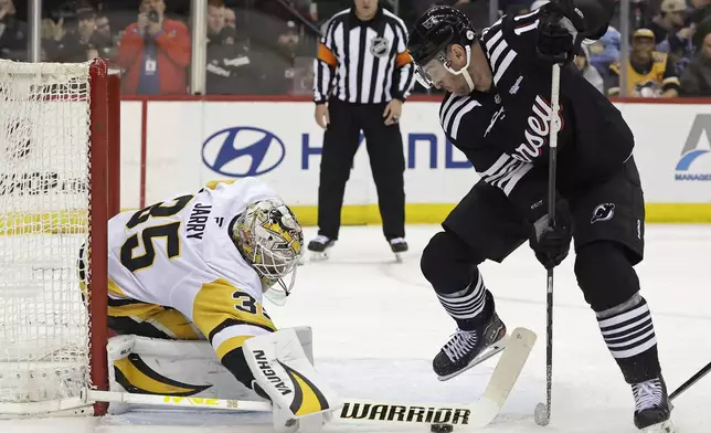 Pittsburgh Penguins goaltender Tristan Jarry, left, stops a shot by New Jersey Devils right wing Stefan Noesen (11) in the second period of an NHL hockey game Friday, April 11, 2025, in Newark, N.J. (AP Photo/Adam Hunger)