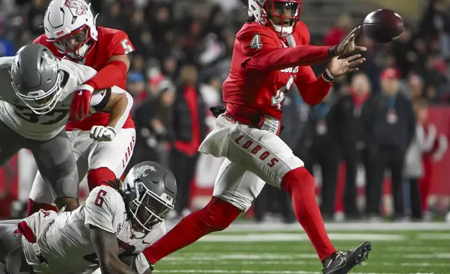 FILE - New Mexico quarterback Devon Dampier, right, pitches the ball as Washington State's Adrian Wilson (6) defends during an NCAA college football game Saturday Nov. 16, 2024, in Albuquerque, N.M. (AP Photo/Roberto E. Rosales, File)
