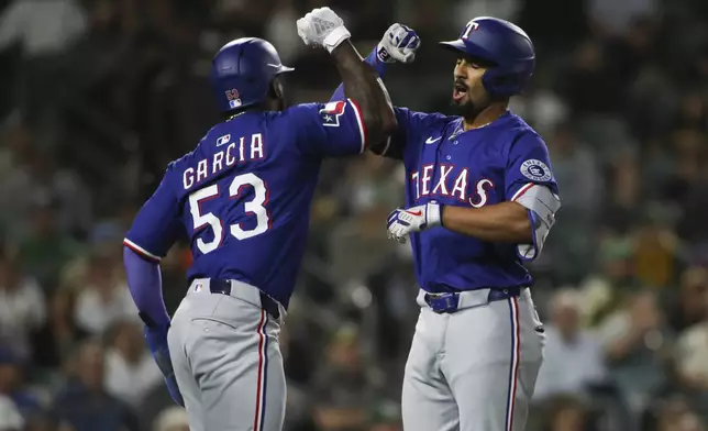 Texas Rangers' Marcus Semien, right, celebrates with teammate Adolis García (53) after hitting a three-run home run against the Athletics during the fifth inning of a baseball game Tuesday, April 22, 2025, in West Sacramento, Calif. (AP Photo/Scott Marshall)