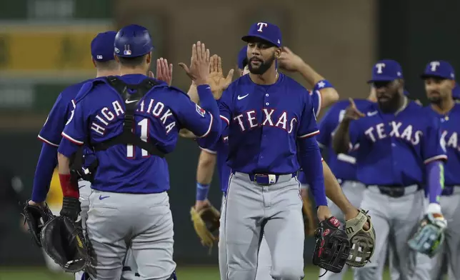 Texas Rangers Leody Taveras, center, high-fives catcher Kyle Higashioka (11) after their victory over the Athletics in a baseball game Tuesday, April 22, 2025, in West Sacramento, Calif. (AP Photo/Scott Marshall)