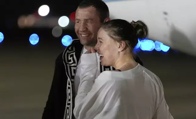 Ksenia Karelina smiles with her fiancé, professional boxer Chris van Heerden, as she arrives Thursday, April 10, 2025, at Joint Base Andrews, Md. (AP Photo/Alex Brandon)