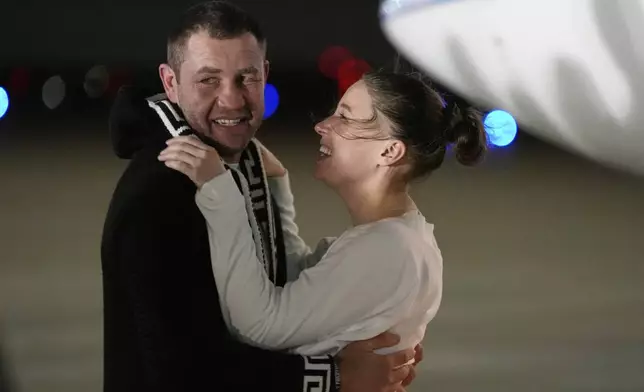 Ksenia Karelina hugs her fiancé, professional boxer Chris van Heerden, as she arrives Thursday, April 10, 2025, at Joint Base Andrews, Md. (AP Photo/Alex Brandon)