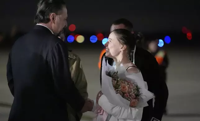 Ksenia Karelina greets Sebastian Gorka, left, as she arrives Thursday, April 10, 2025, at Joint Base Andrews, Md. (AP Photo/Alex Brandon)