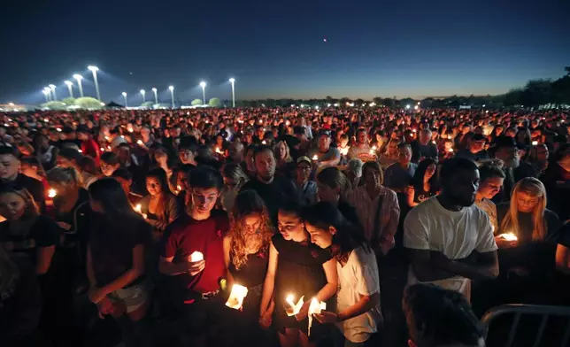 FILE - People attend a candlelight vigil for the victims of a shooting at Marjory Stoneman Douglas High School, in Parkland, Fla., Feb. 15, 2018. (AP Photo/Gerald Herbert, File)