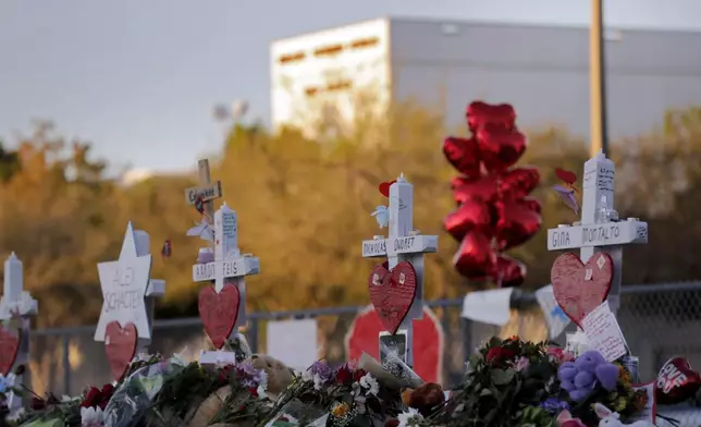 FILE - A memorial is stands outside the Marjory Stoneman Douglas High School where 17 students and faculty were killed in a mass shooting in Parkland, Fla, Feb. 19, 2018. (AP Photo/Gerald Herbert, File)