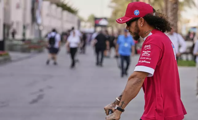 Ferrari driver Lewis Hamilton of Britain rides a scooter through the paddock ahead of the Formula One Bahrain Grand Prix at the Bahrain International Circuit in Sakhir, Thursday, April 10, 2025. (AP Photo/Darko Bandic)