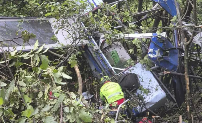 In this photo released by the Italian Alpine and Speleological Rescue Corps on Friday, April 18, 2025, rescuers reach for the smashed gondola of the Mt. Faito cablecar near Naples in southern Italy connecting Castellammare di Stabia to the top of Mt. Faito, that was carrying tourists, on Thursday when the cable snapped, killing at least four people and injuring one. (Soccorso Alpino e Speleologico via AP, HO)