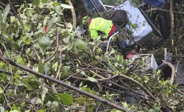 In this photo released by the Italian Alpine and Speleological Rescue Corps on Friday, April 18, 2025, rescuers reach for the smashed gondola of the Mt. Faito cablecar near Naples in southern Italy connecting Castellammare di Stabia to the top of Mt. Faito, that was carrying tourists, on Thursday when the cable snapped, killing at least four people and injuring one. (Soccorso Alpino e Speleologico via AP, HO)