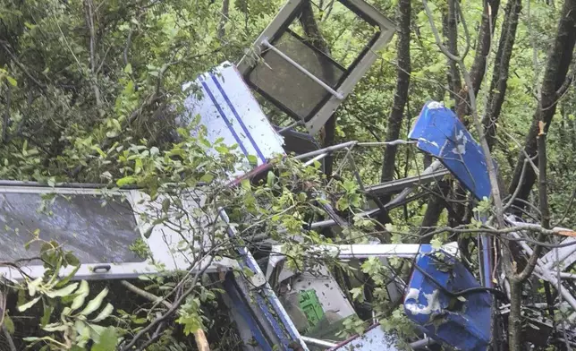 In this photo released by the Italian Alpine and Speleological Rescue Corps on Friday, April 18, 2025, rescuers reach for the smashed gondola of the Mt. Faito cablecar near Naples in southern Italy connecting Castellammare di Stabia to the top of Mt. Faito, that was carrying tourists, on Thursday when the cable snapped, killing at least four people and injuring one. (Soccorso Alpino e Speleologico via AP, HO)