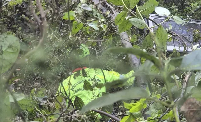 In this photo released by the Italian Alpine and Speleological Rescue Corps on Friday, April 18, 2025, rescuers reach for the smashed gondola of the Mt. Faito cablecar near Naples in southern Italy connecting Castellammare di Stabia to the top of Mt. Faito, that was carrying tourists, on Thursday when the cable snapped, killing at least four people and injuring one. (Soccorso Alpino e Speleologico via AP, HO)