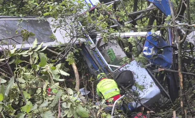 In this photo released by the Italian Alpine and Speleological Rescue Corps on Friday, April 18, 2025, rescuers reach for the smashed gondola of the Mt. Faito cablecar near Naples in southern Italy connecting Castellammare di Stabia to the top of Mt. Faito, that was carrying tourists, on Thursday when the cable snapped, killing at least four people and injuring one. (Soccorso Alpino e Speleologico via AP, HO)