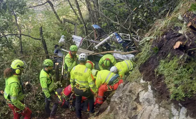In this photo released by the Italian Alpine and Speleological Rescue Corps on Friday, April 18, 2025, rescuers reach for the smashed gondola of the Mt. Faito cablecar near Naples in southern Italy connecting Castellammare di Stabia to the top of Mt. Faito, that was carrying tourists, on Thursday when the cable snapped, killing at least four people and injuring one. (Soccorso Alpino e Speleologico via AP, HO)