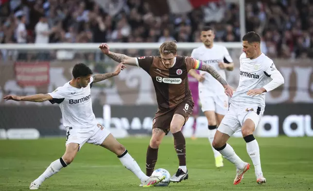 St. Pauli's Eric Smith challenged by Leverkusen's Exequiel Palacios, left, and Patrik Schick during the Bundesliga soccer match between FC St. Pauli and Bayer Leverkusen at Millerntor-Stadion, Hamburg, Germany, Sunday April 20, 2025. (Christian Charisius/dpa via AP)