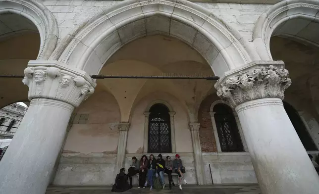 Tourists take a break in San Marco square in Venice, Italy, Friday, April 18, 2025, Venice on Friday launches for a second year a pilot program to charge day-trippers an entrance fee. (AP Photo/Antonio Calanni)