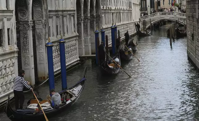 Gondola sail in a canal in Venice, Italy, Friday, April 18, 2025, Venice on Friday launches for a second year a pilot program to charge day-trippers an entrance fee. (AP Photo/Antonio Calanni)