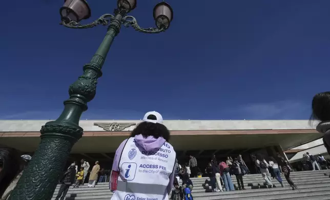 Stewards check tourists' QR codes outside the main train station in Venice, Italy, Friday, April 18, 2025, as the city for a second year is charging day-trippers an arrivals tax. (AP Photo/Antonio Calanni)