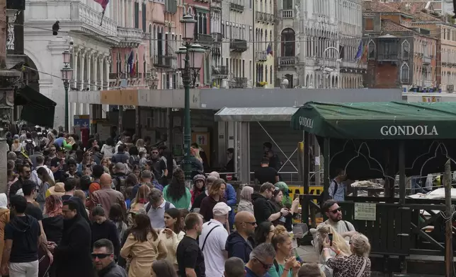 Tourists walk in Venice, Italy, Friday, April 18, 2025, Venice on Friday launches for a second year a pilot program to charge day-trippers an entrance fee. (AP Photo/Antonio Calanni)