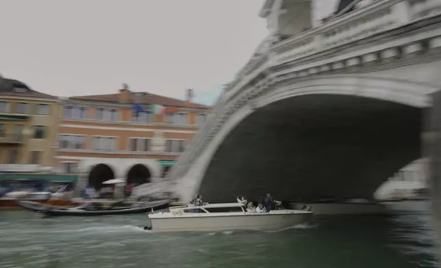 A taxi sails under the Rialto Bridge "Ponte di Rialto" in Venice, Italy, Friday, April 18, 2025, Venice on Friday launches for a second year a pilot program to charge day-trippers an entrance fee. (AP Photo/Antonio Calanni)