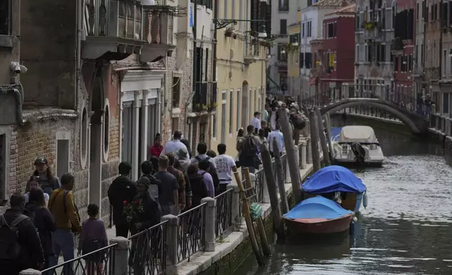 Tourists visit in Venice, Italy, Friday, April 18, 2025, Venice on Friday launches for a second year a pilot program to charge day-trippers an entrance fee. (AP Photo/Antonio Calanni)