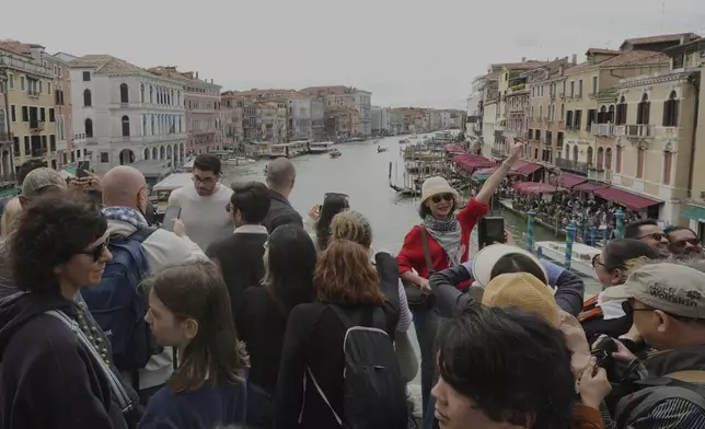 Tourists take pictures on Rialto Bridge "Ponte di Rialto" in Venice, Italy, Friday, April 18, 2025, Venice on Friday launches for a second year a pilot program to charge day-trippers an entrance fee. (AP Photo/Antonio Calanni)